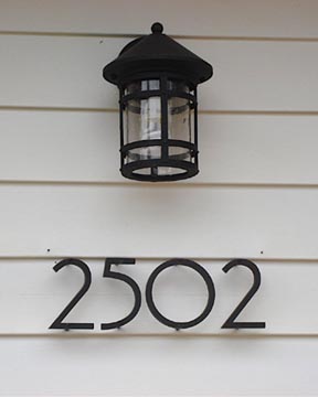 So geht es natürlich auch: Wandaußenlampe und Hausnummer. Wichtig wäre für diese Variante, die Lampe mit einem Bewegungsmelder auszustatten, damit die Hausnummer tatsächlich beleuchtet ist, sobald sich jemand dem Haus nähert. Gefunden bei http://www.nachi.org/house-numbers.htm
