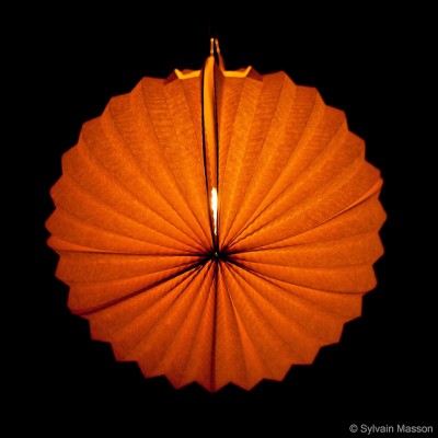 Ein in der Dunkelheit orange leuchtender,. runder Lampion