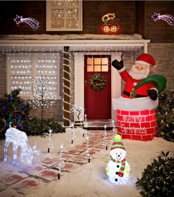 In einem Vorgarten stehen leuchtende Figuren: ein Weihnachtsmann im Schornstein, ein Schneemann, ein Rentier, dazu viele Lichterketten und andere Leuchten.
