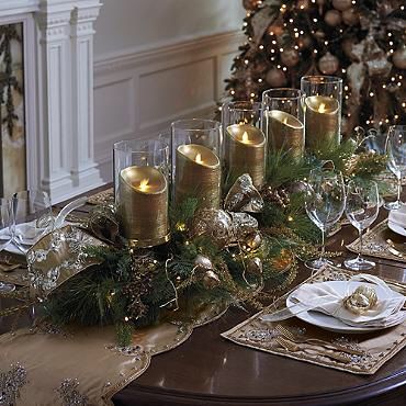 Eine Tafel ist schon gedeckt mit Geschirr, Platzsets und in der Mitte 5 goldenen Kerzen, Tannenzweigen und einer Lichterkette.