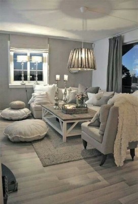 Ein Wohnzimmer im Landhausstil - natürliche helle Farben, viele Holzmöbel - hat eine Hängelampe mit einem sanften Lampenschirm