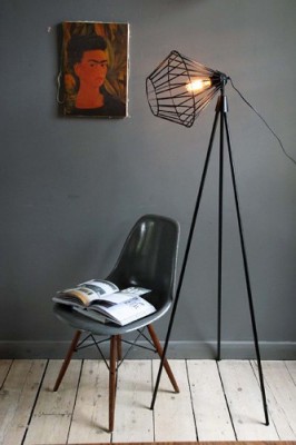 In einem cleanen, modernen Wohnzimmer steht vor einer dunkelgrauen Wand eine Stehleselampe mit geometrischem Lampenschirm