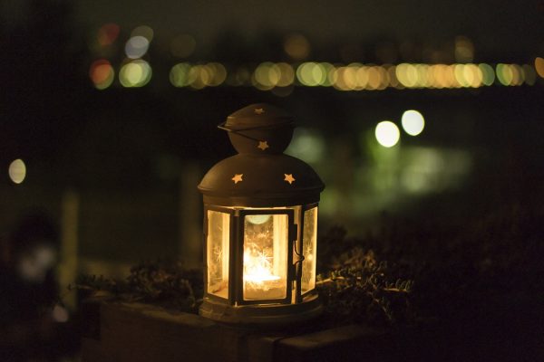 eine leuchtende Laterne mit Teelicht darin steht nachts draußen.