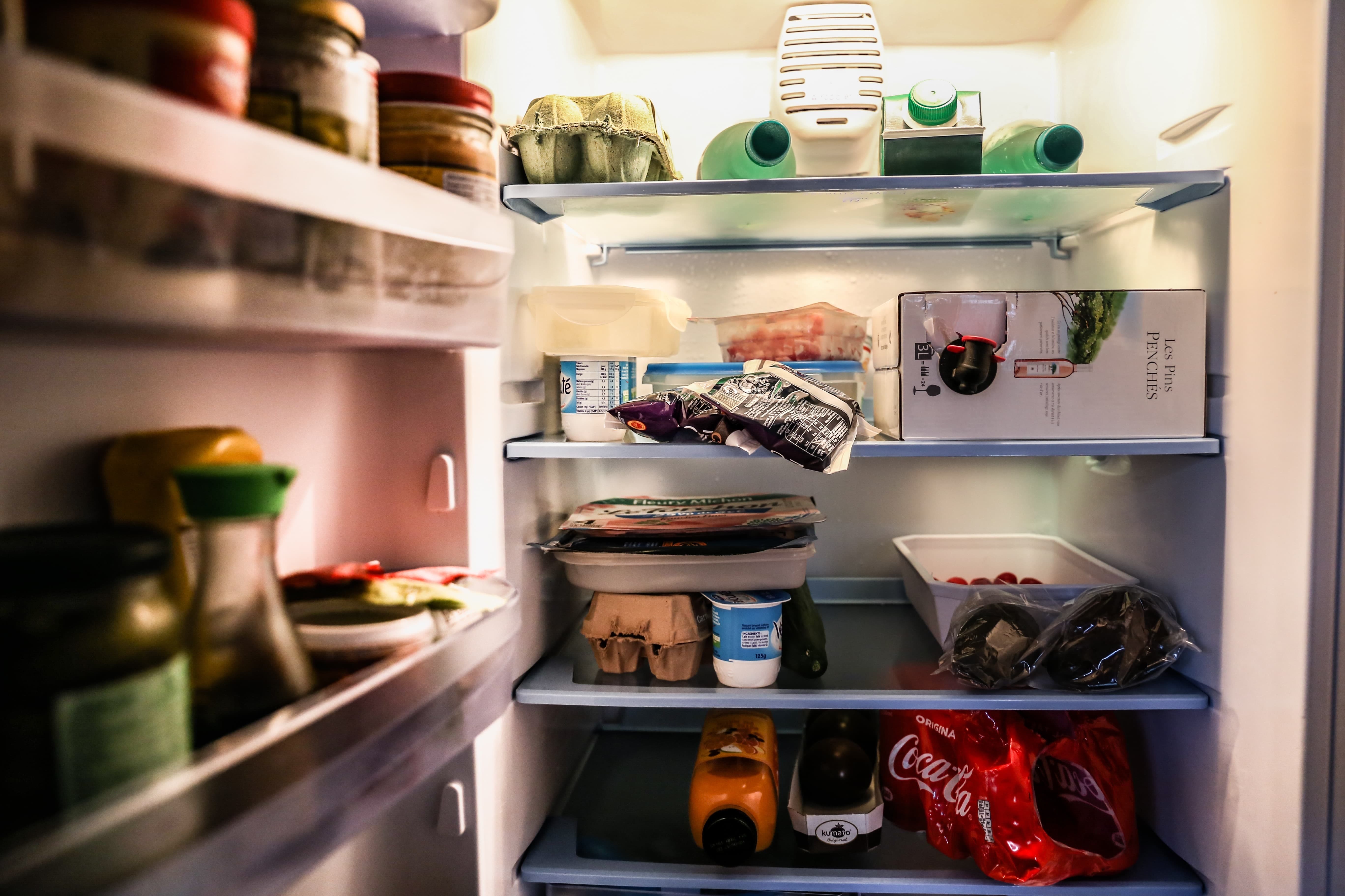 Ein offener Kühlschrank, dessen bunter Inhalt an Lebensmitteln beleuchtet ist