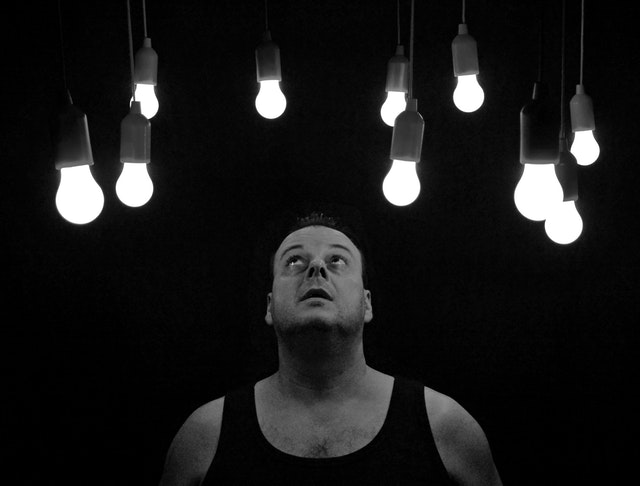 Mehrere LED Lampen hängen von oben herunter und ein Mann schaut sie staunend von unten an