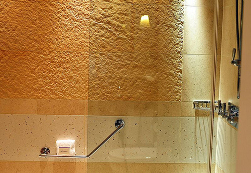 Eine kunstvoll angestrahlte Wand über einer Badewanne mit Glastrennwand