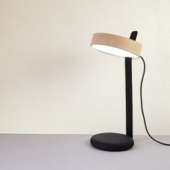 Eine Schreibtischlampe mit einem Lampenschirm aus Holz