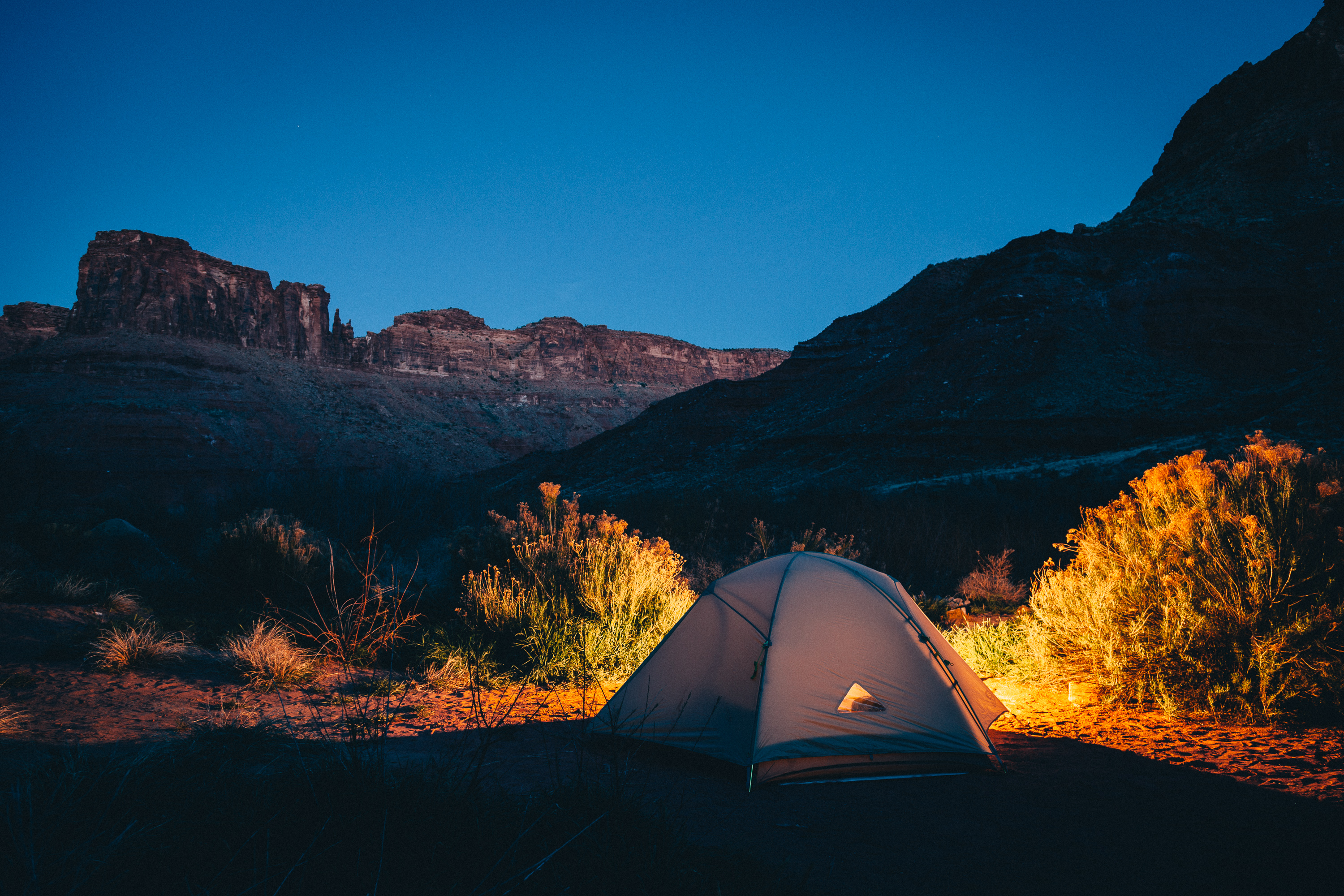 Ein Zelt wird nachts in der freien Natur erleuchtet - wahrscheinlich mit einem Akkustrahler.