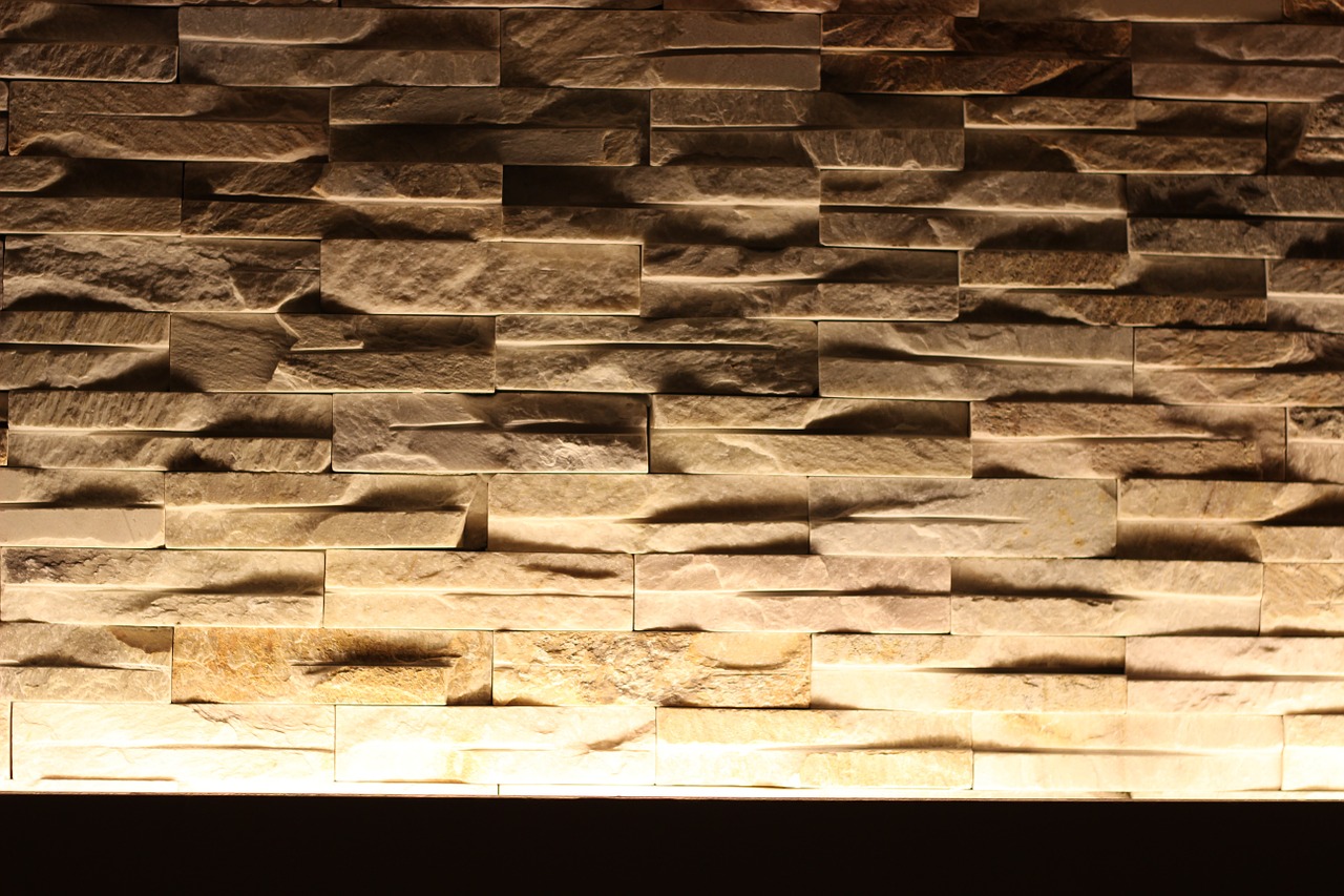 Eine Wand aus Natursteinen in einer Wohnung wird durch indirektes Licht von unten erleuchtet