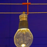 Eine Glühbirne hängt an zwei stromleitenden Seilen