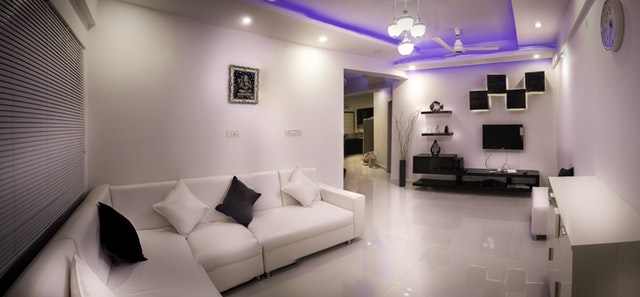 Ein weiß gestalteter Raum mit Couch und anderen Einrichtungsgegenständen wird mit verschiedenen Lichtern beleuchtet.