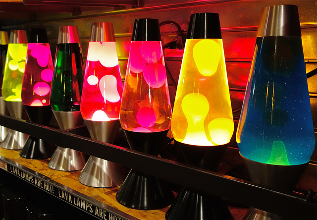Mehrere Lavalampen leuchten in verschiedenen Farben und stehen in einem Regal