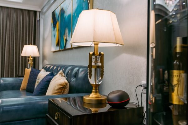 Neben einer blauen Couch stehen goldene Art Deco Tischleuchten