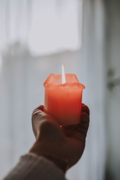 Eine Person hält eine rote Kerze in der Hand