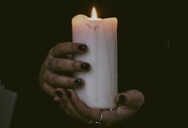 Person hält brennende Kerze in der Hand.