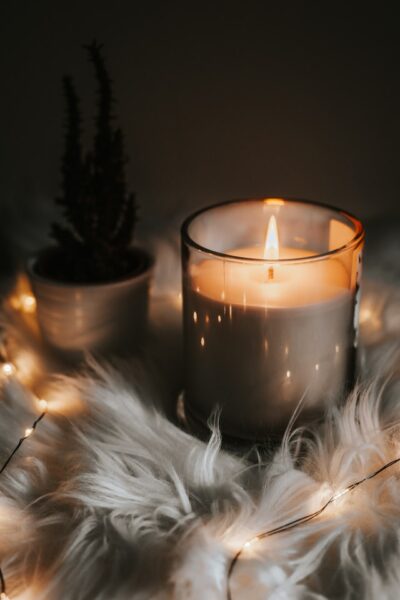 Kerze im Glas auf einem Fell mit Lichterkette drumherum