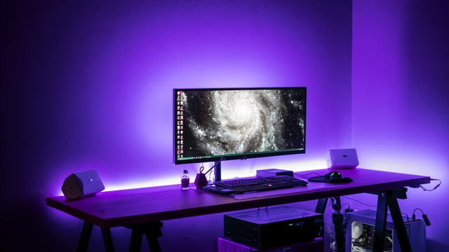 Ein Schreibtisch wird indirekt an der Platte von lila LEDs beleuchtet