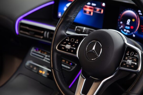Nahaufnahme eines Mercedes-Lenkrads, das Armaturenbrett im Hintergrund wird durch LED lila beleuchtet