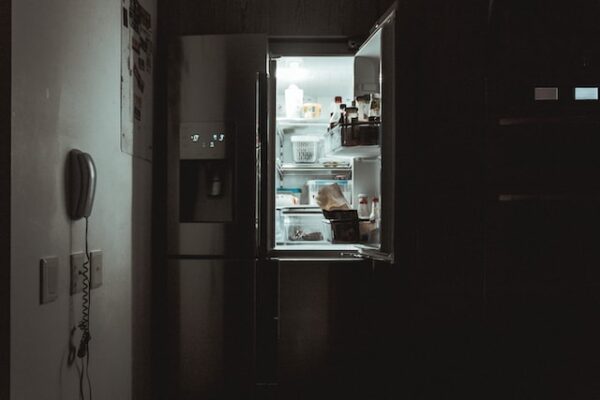 Ein Kühlschrank in einer dunklen Küche, die Tür steht offen